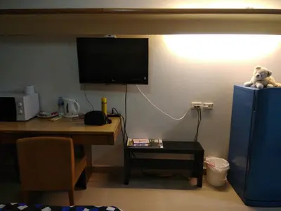 a room with a desk and a television on a wall at Savi Rooms Premium 1 Near Bkk Piyavet Hospital in Bangkok