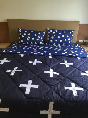 a bed with a blue comforter with crosses on it at Savi Rooms Premium studio near bkk Piyavet hospital near most famous pubs in Bangkok