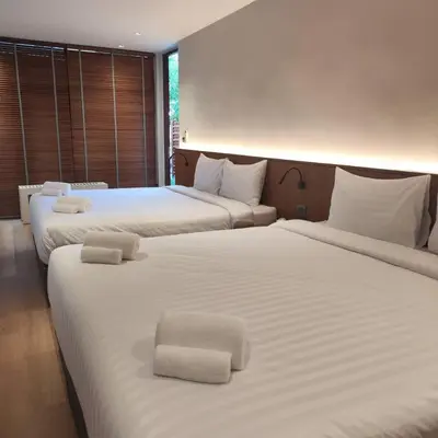 two beds in a hotel room with white sheets at ROOMS at Number60 Khaosan Bangkok in Bangkok