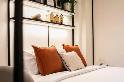 a bed with orange and white pillows on it at Pillow B Hotel in Ban Zong Katiam