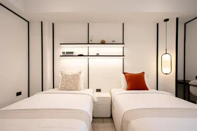 two beds in a room with white walls at Pillow B Hotel in Ban Zong Katiam
