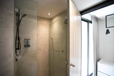 a shower with a glass door in a bathroom at Pillow B Hotel in Ban Zong Katiam