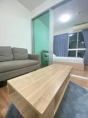 a living room with a couch and a wooden table at M Stay in Nonthaburi