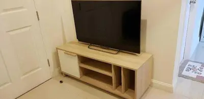 a flat screen tv sitting on top of a wooden stand at M Stay in Nonthaburi
