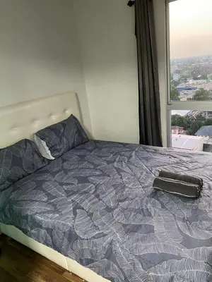 a bed in a bedroom with a large window at M Stay in Nonthaburi