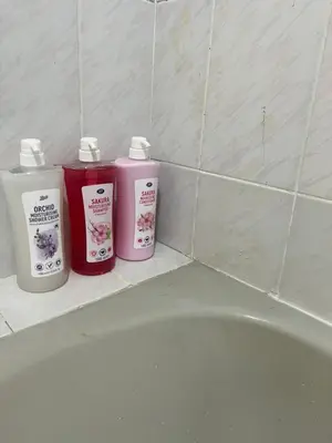 three bottles of detergent sitting next to a bath tub at Regent Srinakarin18 in Amphoe Phra Khanong