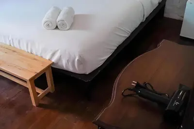 a bed with two towels on it with a table at XX Mitr Inn Yaowarat 2 - มิตร อินน์ เยาวราช in Bangkok