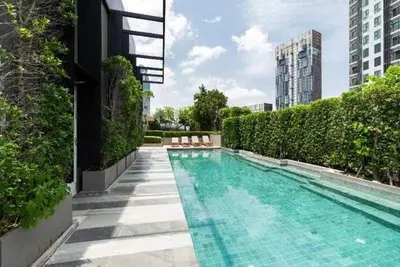 a swimming pool with chairs next to a building at bts thong lor \u6e38\u6cf3\u6c60-\u514d\u8d39\u65e0\u7ebf\u7f51\u7edc in Bang Khen