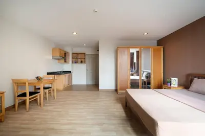 a bedroom with a bed and a table and a kitchen at 181 Ekkamai Studio Apartment in Bangkok