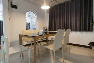 a dining room with a table and white chairs at \u66fc\u8c37\u8f89\u714c \u65fa\u4e2d\u5e26\u9759 \u5e26\u5ead\u9662\u76843\u4e2a\u623f\u95f4\u72ec\u7acb\u522b\u5885 \u9884\u8ba25\u5929\u4ee5\u4e0a\u63d0\u4f9b\u514d\u8d39\u63a5\u673a\u4e00\u6b21 in Bang Rak