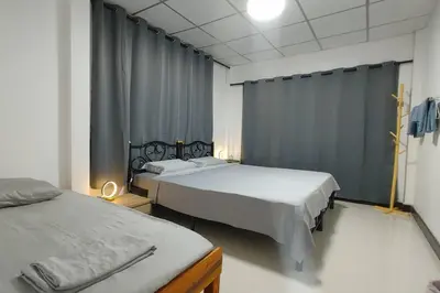 a bedroom with two beds and a curtain at \u66fc\u8c37\u8f89\u714c \u65fa\u4e2d\u5e26\u9759 \u5e26\u5ead\u9662\u76843\u4e2a\u623f\u95f4\u72ec\u7acb\u522b\u5885 \u9884\u8ba25\u5929\u4ee5\u4e0a\u63d0\u4f9b\u514d\u8d39\u63a5\u673a\u4e00\u6b21 in Bang Rak