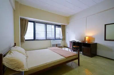 a bedroom with a bed and a desk and window at Petch Tower Ekkamai in Bangkok