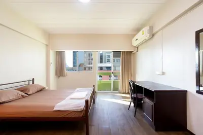 a bedroom with a bed and a desk and a window at Petch Tower Ekkamai in Bangkok