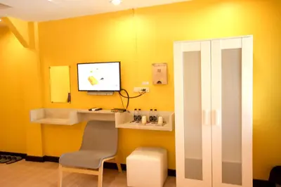 a yellow room with a chair and a tv on a wall at Room@Vipa in Bangkok