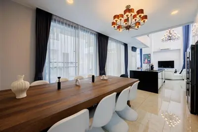 a dining room with a large wooden table and white chairs at \u66fc\u8c37\u5e02\u4e2d\u5fc3\u4e03\u5367\u5ba4\u72ec\u680b\u8c6a\u534e\u6cf3\u6c60\u522b\u5885 in Bangkok