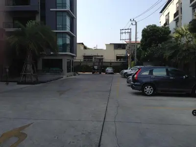 a parking lot with cars parked next to a building at Ipremium Sukhumvit 81 Hotel in Bangkok