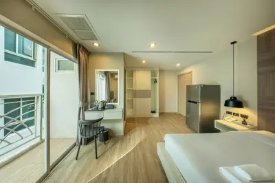 a bedroom with a large bed and a kitchen at Ralph Poshtel Pratunam in Bangkok