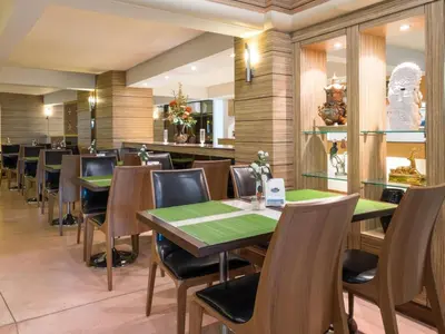 a dining room with green tables and chairs at New Suanmali Hotel in Bangkok