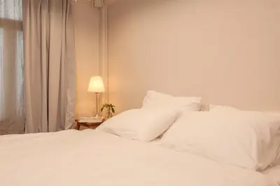 a bedroom with two white beds next to a window at Mana Craft Stay in Bangkok