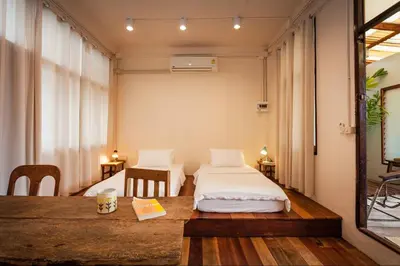 a room with two beds and a wooden table at Mana Craft Stay in Bangkok