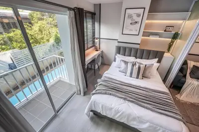 a bedroom with a bed and a balcony at Sense of London BTS Baring in Ban Khlong Samrong
