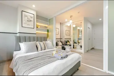 a bedroom with a large bed and a living room at Sense of London BTS Baring in Ban Khlong Samrong