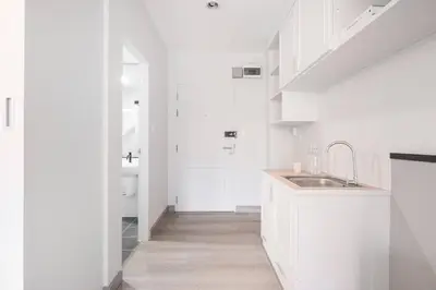 a white kitchen with white cabinets and a sink at Sense of London BTS Baring in Ban Khlong Samrong