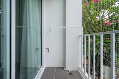 a glass door leading to a balcony with pink flowers at Sense of London BTS Baring in Ban Khlong Samrong