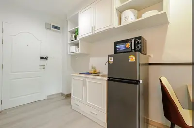 a kitchen with a stainless steel refrigerator and a table at Sense of London BTS Baring in Ban Khlong Samrong