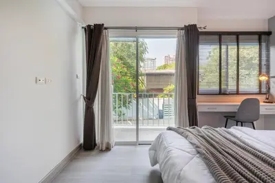 a bedroom with a bed and a desk and a window at Sense of London BTS Baring in Ban Khlong Samrong