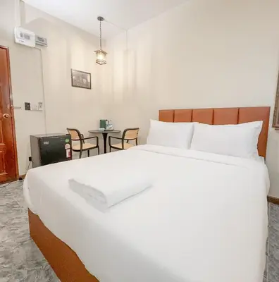 a large white bed in a room with a table at JB Home Bangkok - Victory monument in Bangkok