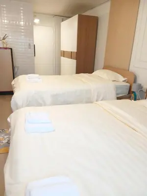 two beds in a hotel room with white sheets at NK hostel 18 in Thung Si Kan