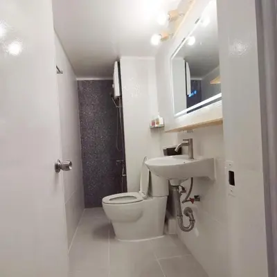 a white bathroom with a toilet and a sink at NK hostel 18 in Thung Si Kan