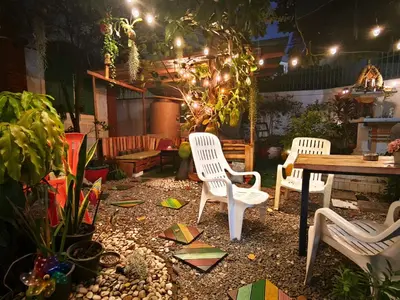 a patio with three white chairs and a table at Green Garden Hostel in Bangkok