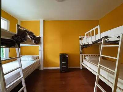 a room with two bunk beds and a yellow wall at Green Garden Hostel in Bangkok