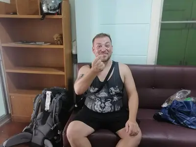 a man sitting on a couch with his finger to his mouth at Green Garden Hostel in Bangkok