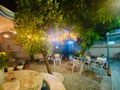 a patio with tables and chairs and a tree at Green Garden Hostel in Bangkok