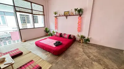 a bedroom with a red bed in a room with windows at Baan YentaFo - Pink House 3rd floor in Chinatown