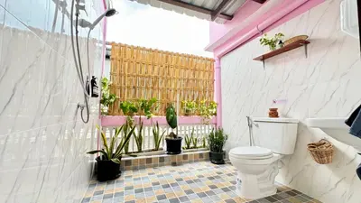 a bathroom with a toilet and a window with potted plants at Baan YentaFo - Pink House 4th floor in Chinatown