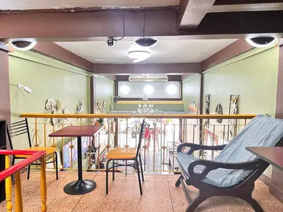 a room with chairs and tables and a balcony at Yuma Tashi Hostel in Bangkok