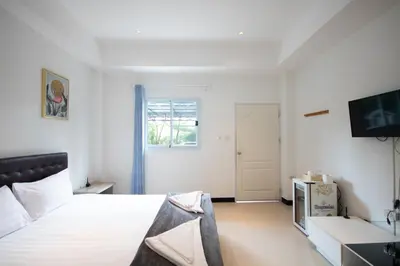 a white bedroom with a bed and a television at Arttra Villa in Bang Chak