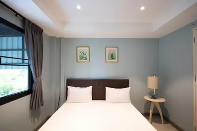 a bedroom with a bed with white sheets and a window at Arttra Villa in Bang Chak