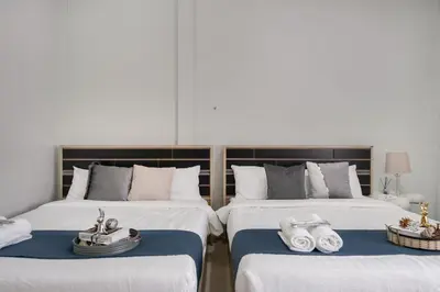 two beds in a room with white sheets and towels at 4BR house MRT subway 250m Chatujak Market wi-fi in Bangkok