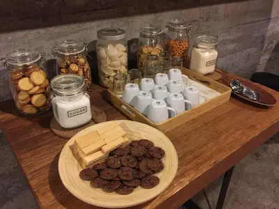 a wooden table with cookies and jars of food at BED STATION Hostel Ratchthewi in Bangkok