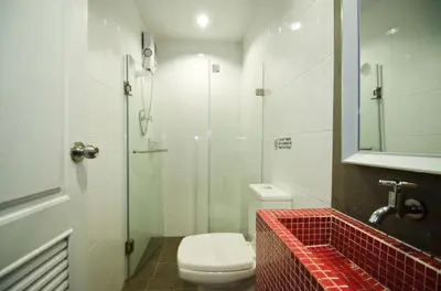 a bathroom with a toilet and a glass shower at DI Place in Bangkok