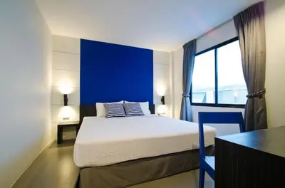a bedroom with a large bed with a blue wall at DI Place in Bangkok