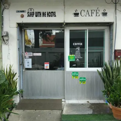 a store front of a cafe with signs on the door at Sleep at home hostel in Bangkok