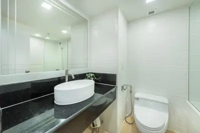 a white bathroom with a sink and a toilet at Neom Town Residence in Bangkok