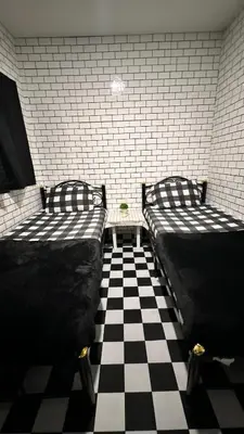 two beds in a room with a checkered floor at White House Hostel Khaosan in Bangkok