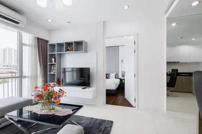 a white living room with a tv and a couch at Shine Sukhumvit 43 Apathotel Phrompong in Bangkok